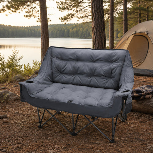 Gray padded double camping loveseat fully opened at a lakeside campsite